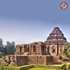 an ancient building in the middle of a lush green field with trees and bushes around it