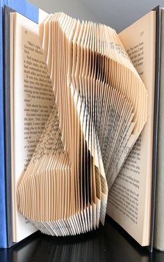 an open book with folded pages sitting on top of a table