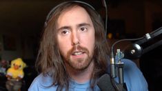 a man with long hair wearing headphones is in front of a microphone and looks at the camera