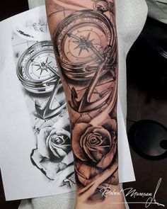 a black and white tattoo on the arm of a person with a compass, rose and compass