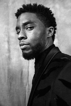 a black and white photo of a man with dreadlocks looking at the camera