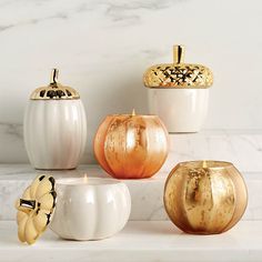 four white and gold pumpkins sitting next to each other on a marble counter top