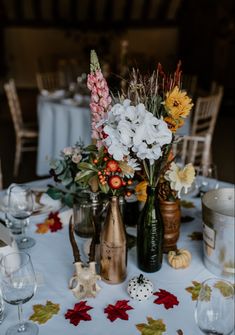 a table topped with vases filled with flowers next to glasses and plates on top of a table