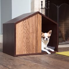 a small dog sitting in a wooden kennel on the floor next to a rug