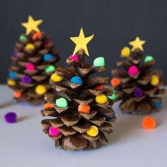 three pine cones decorated with christmas lights and colored balls are sitting next to each other