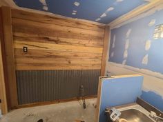 an unfinished kitchen with blue walls and wood paneling on the wall behind the sink