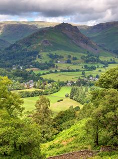 the valley is surrounded by lush green hills and trees, with mountains in the distance