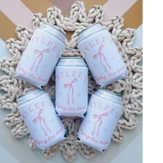 four white jars with pink writing on them sitting in front of a circular doily