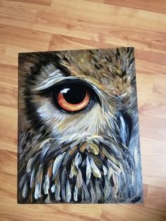 an owl's eye is shown in this painting on a wood flooring surface