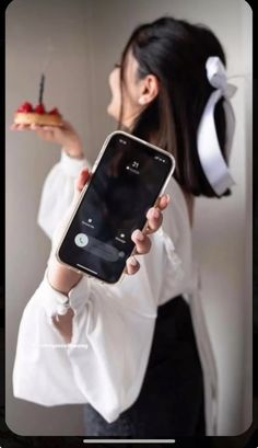 a woman holding up a cell phone in front of her face with an apple on it