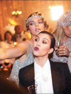 three women dressed in flappers and gats pose for the camera at a party