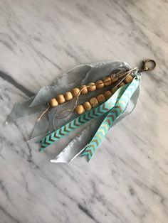 three feathers with beads on them sitting on a marble surface