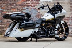 a white and black motorcycle parked in front of a brick wall