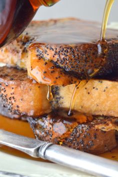 someone pouring honey onto some bread on a plate