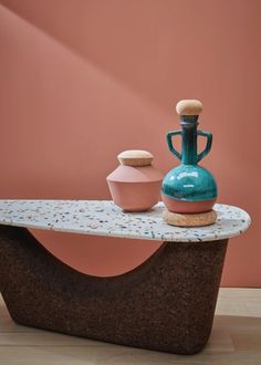 two vases sitting on top of a stone bench in front of a pink wall