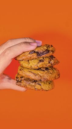 a hand holding a stack of cookies on an orange background