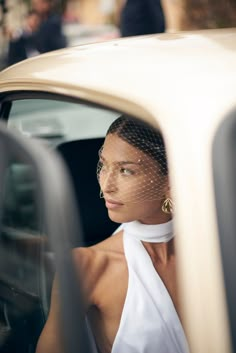 a woman sitting in the back seat of a car wearing a white dress and veil