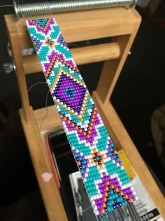 a colorful beaded tie sitting on top of a wooden stand next to a sewing machine