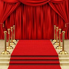 a red carpeted stage with gold poles and barriers in front of a red curtain