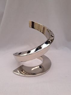 a silver ring with dots on it sitting on top of a white surface, in front of a white background