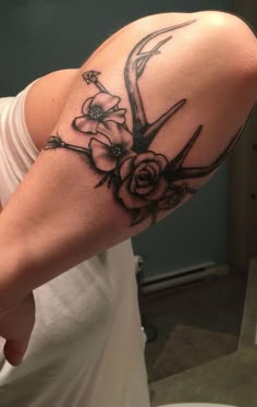 a person with a tattoo on their arm holding a clock and flowers in the background