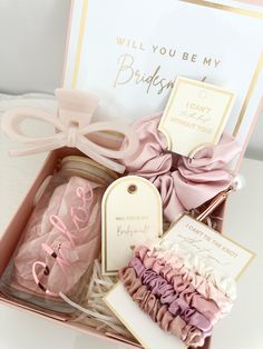 a pink box filled with lots of different items next to a card and some tags