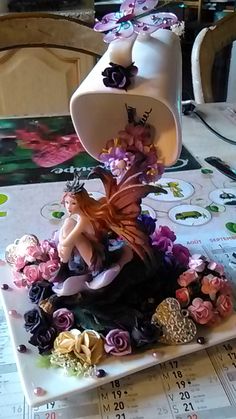 there is a figurine sitting on top of a plate with flowers around it