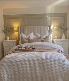 a bed with white sheets and pillows in a bedroom next to two lamps on either side of the bed