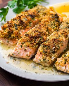 two salmon fillets on a plate with lemon wedges and parsley garnish