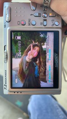 a person holding up a digital camera with the image of a woman making a peace sign