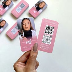 a person holding up a pink card with photos on it and qr in the background