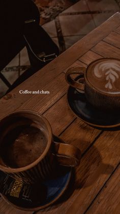 two cups of coffee sitting on top of a wooden table