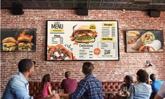 people sitting at tables in front of menus on the wall and brick walls behind them