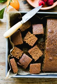 a pan filled with brownies and raspberries on top of a wooden table