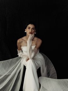 a woman in white is sitting on the floor with her veil flowing around her neck