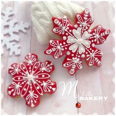 two red and white snowflake cookies sitting next to each other on a table