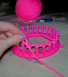 a ball of yarn is being held by a person's hand over a pink object