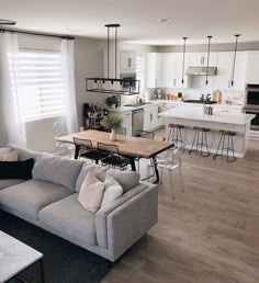 a living room filled with furniture next to a kitchen and dining room table on top of a hard wood floor