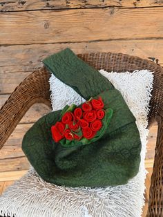 a green bag with red roses on it is sitting on a white towel in a wicker chair