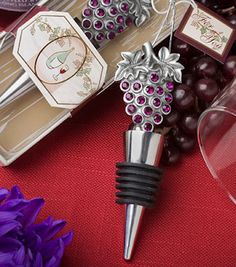 wine bottle stoppers with grapes on them sitting in front of some wine glasses and purple flowers