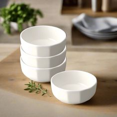 four white bowls sitting on top of a wooden table