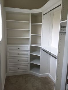 an empty walk in closet with white shelves and drawers