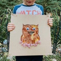 a young boy holding up a piece of paper with an owl on it's face