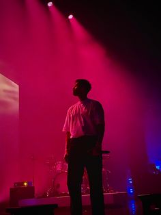 a man standing in front of a stage with purple light on it's side