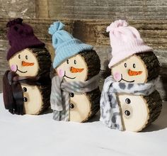 three wooden snowmen wearing hats and scarves