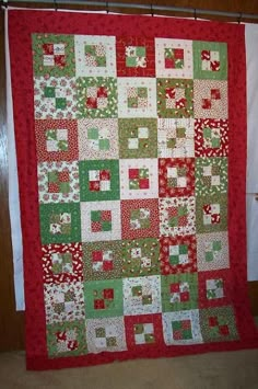 a red and green quilt hanging on a wall