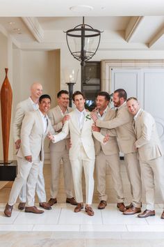 a group of men standing next to each other in front of a chandelier