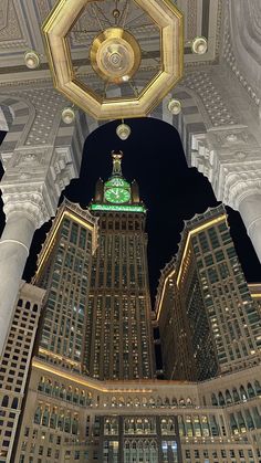 the clock tower is lit up at night in front of other tall buildings with lights on them