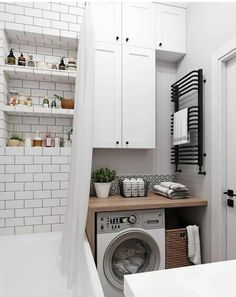 a washer and dryer in a small room with white walls, cabinets and shelving