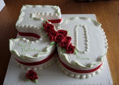 two white cakes with red roses on them are sitting on a wooden table and the number 50 is decorated